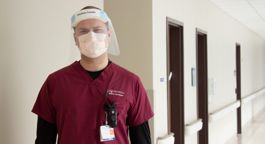 Photo of NC alumnus Connor Kenny wearing PPE and standing in a hospital hallway.