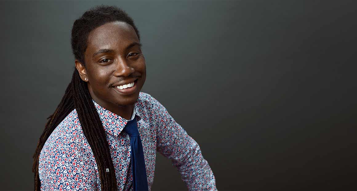 Shane Malcolm smiles, smartly dressed in a tie, floral shirt.