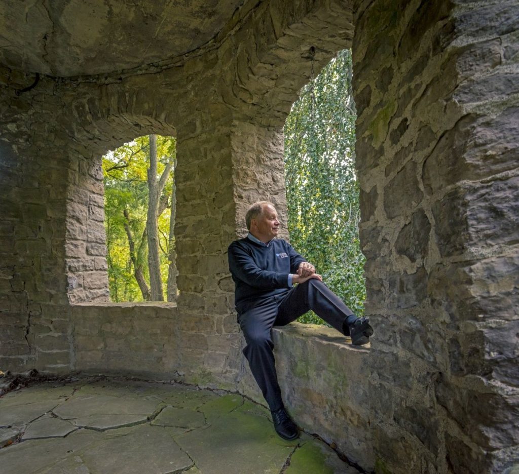 Dan Patterson sits on a stone window ledge overlooking the trees