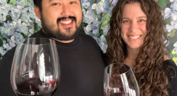 A man and woman hold wine glasses and smile.