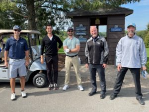 a group of golfers stand in a row in front of a golf cart
