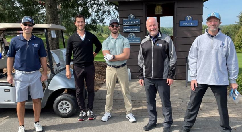 a group of golfers stand in a row in front of a golf cart