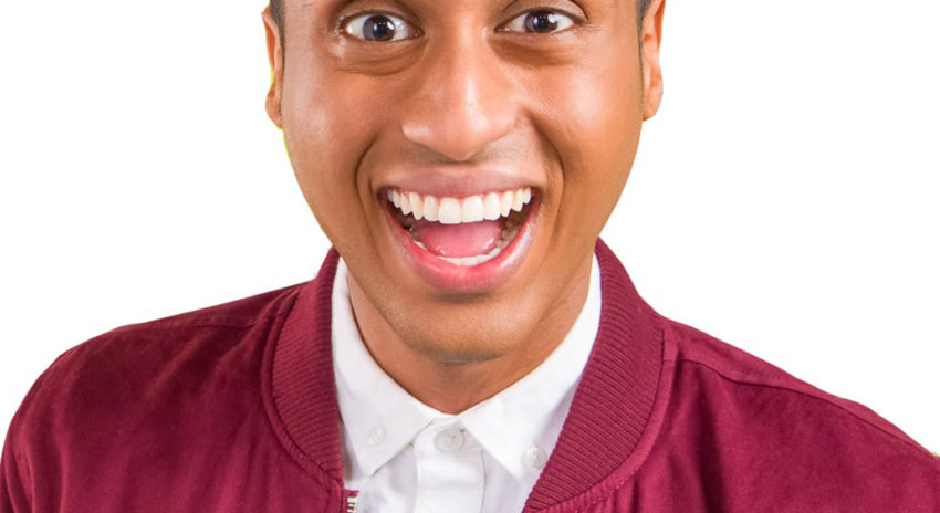 A photo of a young man with brown skin smiling animatedly