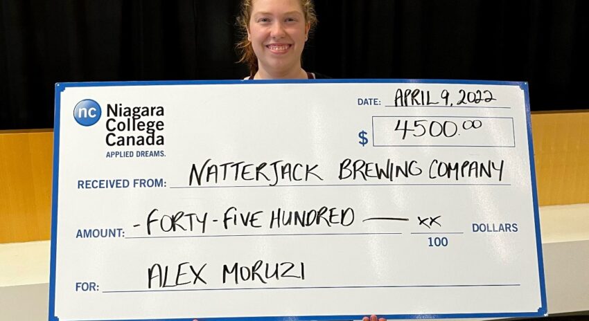 young woman holds oversized cheque in the amount of $4,500
