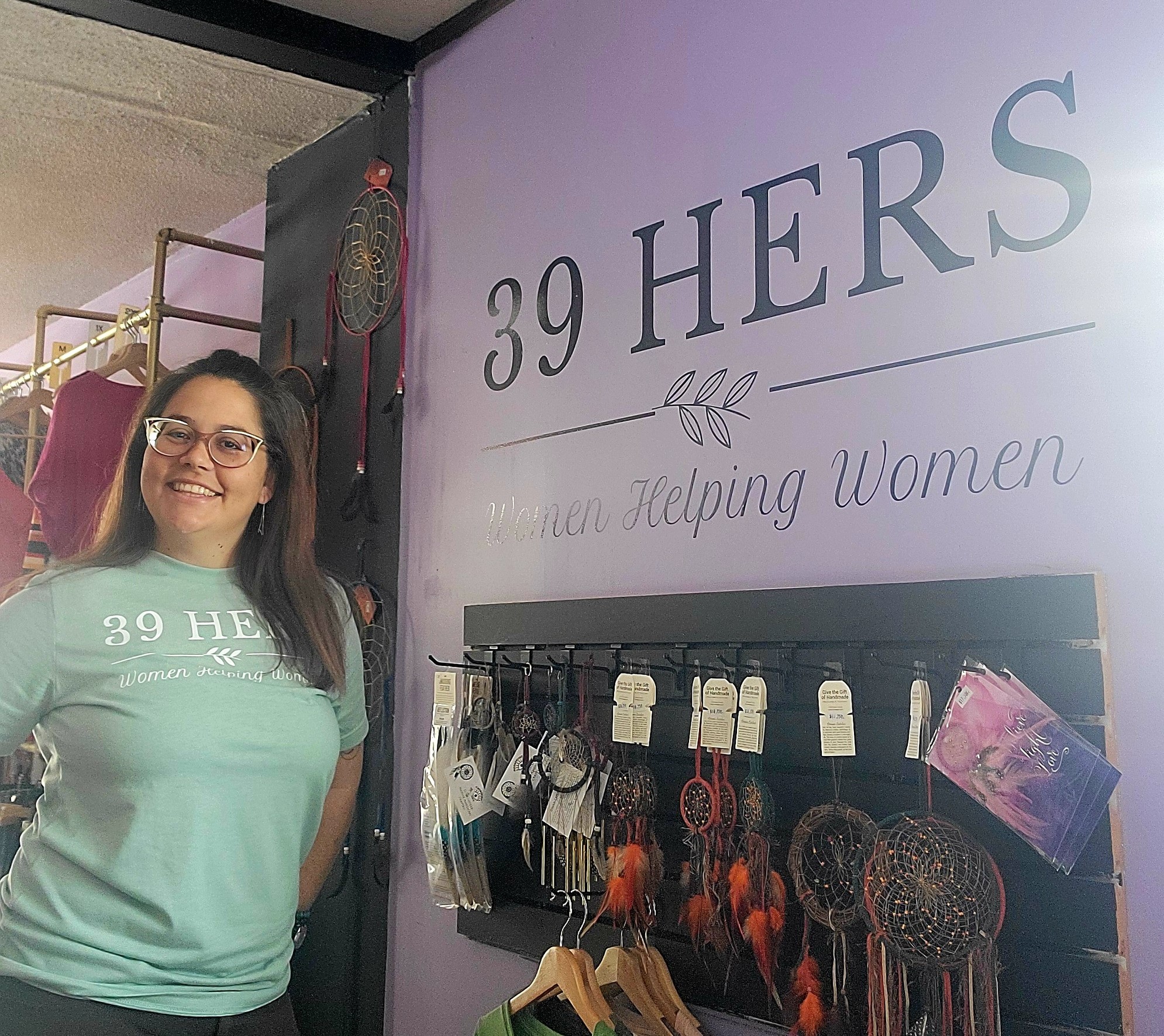 A woman wearing a green shirt stands alongside a wall bearing the words 39 Hers